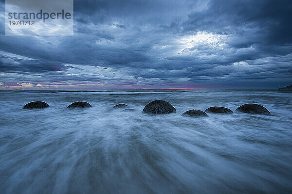 Wellen bewegen sich um Moeraki Boulders entlang eines Abschnitts des Koekohe Beach auf der Südinsel Neuseelands; Hampden  North Otago  Neuseeland