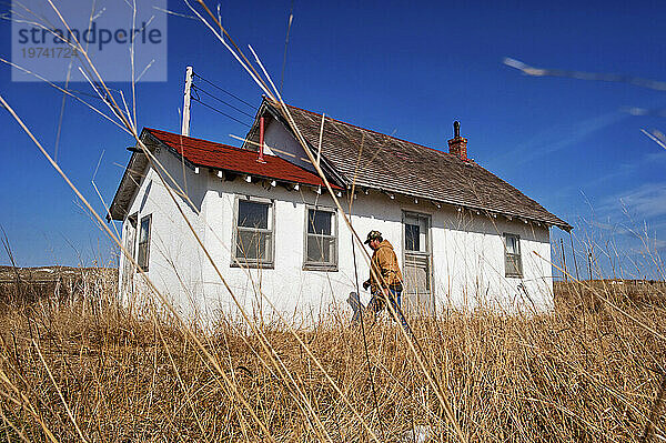 Mann erkundet ein verlassenes Schulhaus mit nur einem Raum in den Nebraska Sandhills  USA; Sandhills  Nebraska  Vereinigte Staaten von Amerika