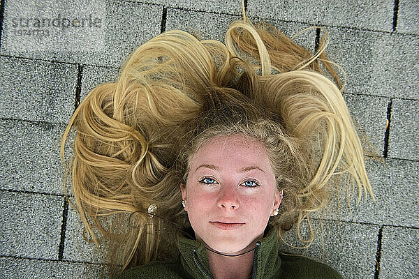 Teenagermädchen mit langen blonden Haaren liegt auf Schindeldach; Elkhorn  Nebraska  Vereinigte Staaten von Amerika