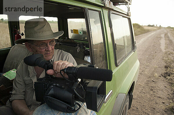 Videofilmer fährt in einem Safari-Geländewagen im Queen-Elizabeth-Nationalpark; Mweya  Uganda