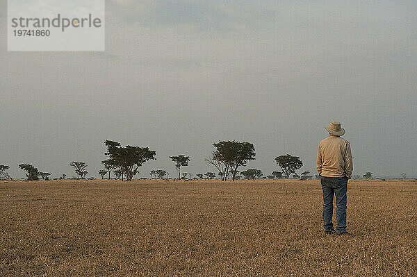 Ein Mann steht allein da und bewundert die Landschaft im Queen-Elizabeth-Nationalpark in Uganda  Afrika; Uganda