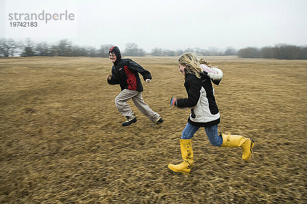 Junge und Mädchen rennen und jagen sich gegenseitig auf einem Feld; Lincoln  Nebraska  Vereinigte Staaten von Amerika.