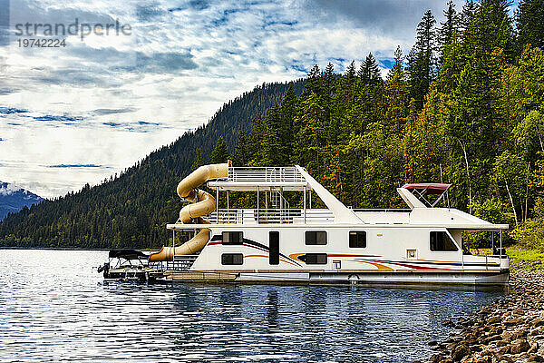 Ein Ferienhausboot  das an einem Dock am Ufer des Shuswap Lake geparkt ist; Shuswap Lake  British Columbia  Kanada