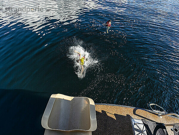 Junge planscht ins Wasser  nachdem er aus dem Ende einer Hausboot-Wasserrutsche am Shuswap Lake gerutscht ist; British Columbia  Kanada