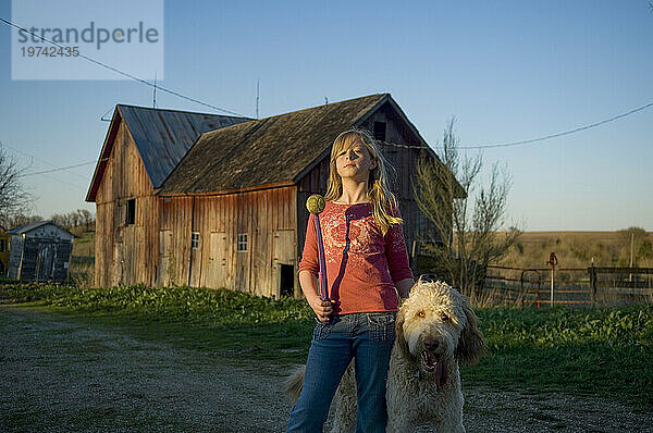 Mädchen steht mit ihrem Hund in der Nähe einer Scheune; Dunbar  Nebraska  Vereinigte Staaten von Amerika
