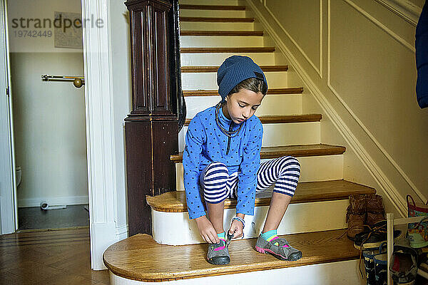 Ein Mädchen im Grundschulalter zieht auf der Treppe ihres Hauses ihre Schuhe an; Washington  District of Columbia  Vereinigte Staaten von Amerika