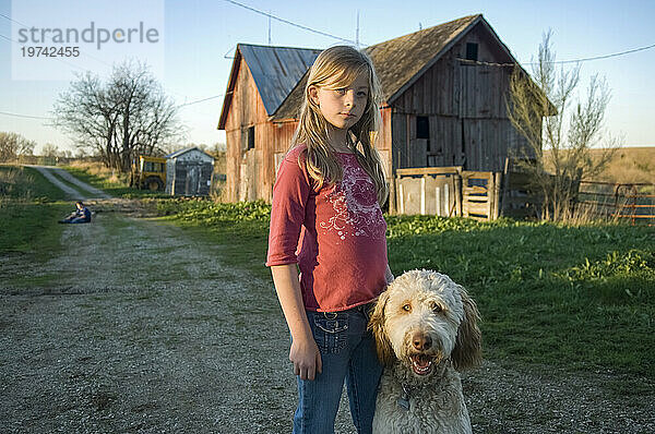 Mädchen steht mit ihrem Hund in der Nähe einer Scheune; Dunbar  Nebraska  Vereinigte Staaten von Amerika