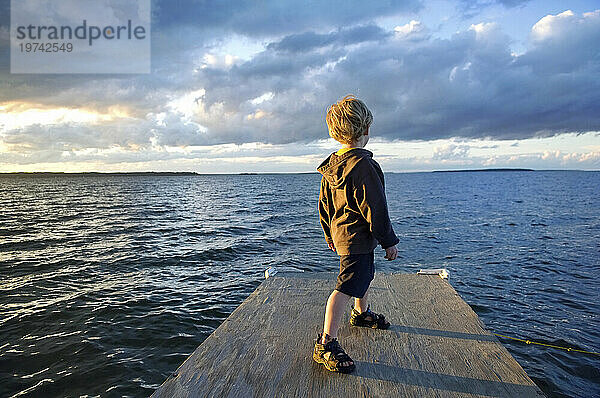 Kleiner Junge auf einem Steg am See in der Abenddämmerung  Leech Lake in Minnesota  USA; Walker  Minnesota  Vereinigte Staaten von Amerika