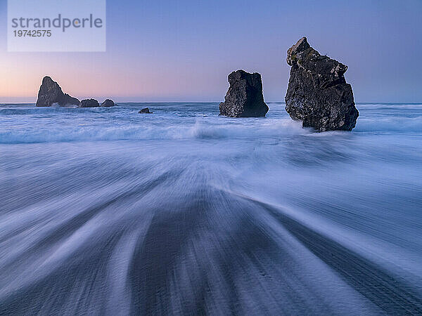 Wellen spülen bei Sonnenuntergang über einen Strand; Haast  Südinsel  Neuseeland