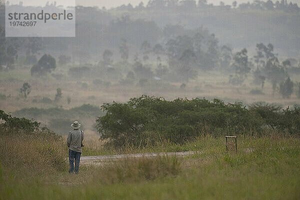 Ein Mann steht allein da und bewundert die Landschaft im Queen-Elizabeth-Nationalpark in Uganda  Afrika; Uganda
