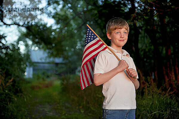 Junger  patriotischer Junge hält eine amerikanische Flagge hoch; Lincoln  Nebraska  Vereinigte Staaten von Amerika