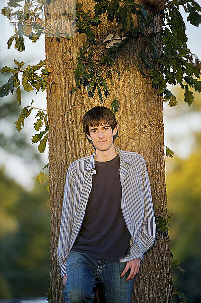 Außenporträt eines Teenagers  der sich an einen Baum lehnt; Lincoln  Nebraska  Vereinigte Staaten von Amerika