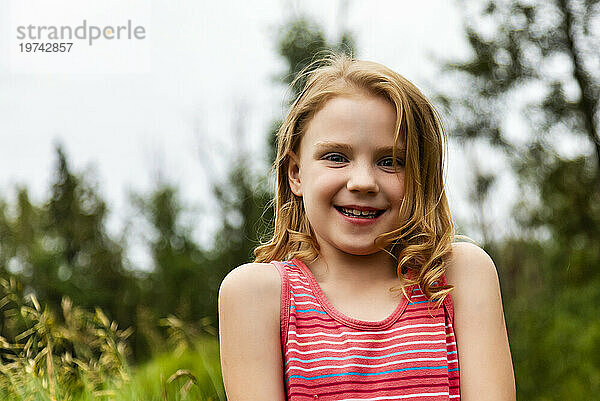 Porträt eines jungen Mädchens in einem Park  das in die Kamera lächelt; Edmonton  Alberta  Kanada