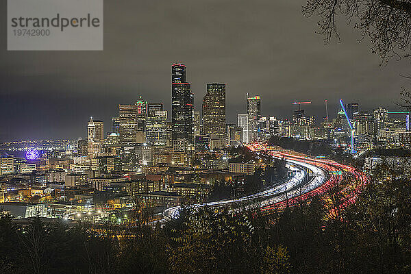 Nachtansicht der Skyline von Seattle mit Verkehr auf der I-5 und dem Seattle Great Wheel ganz links; Seattle  Washington  Vereinigte Staaten von Amerika