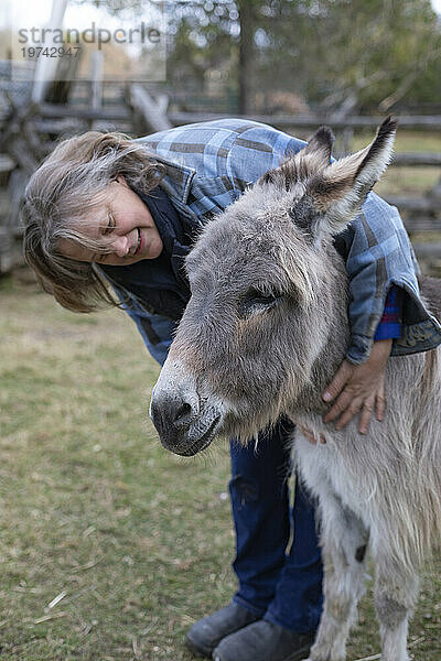 Bäuerin umarmt einen Esel (Equus asinus) auf ihrer Farm  Kara's Animals in Beckwith; Ottawa Valley  Ontario  Kanada