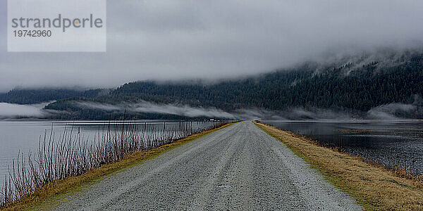 Atemberaubender Blick auf einen Spaziergang entlang des Schotterstraßendamms am Pitt Lake in Maple Ridge an einem grauen  nebligen Tag; Maple Ridge  British Columbia  Kanada