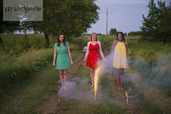 Drei junge Frauen in formeller Kleidung zünden Feuerwerkskörper auf dem Land an; Bennet  Nebraska  Vereinigte Staaten von Amerika
