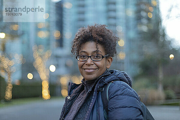Nahaufnahmeporträt einer Frau  die in der Dämmerung draußen in Vancouver steht und in die Kamera lächelt; Vancouver  British Columbia  Kanada