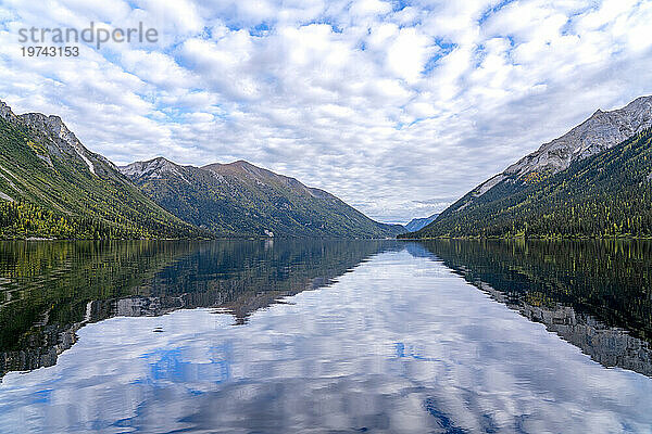 Spiegelungen in einem ruhigen See in der Ruby Range des Yukon. Die Herbstfarben dringen langsam in die Landschaft ein; Yukon  Kanada