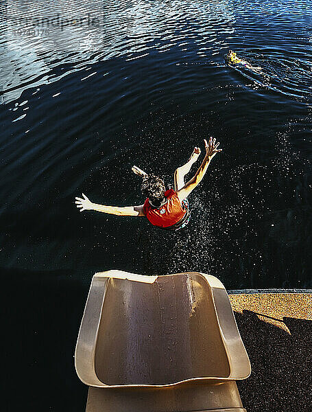 Junge fliegt in der Luft Richtung Wasser  nachdem er am Ende einer Hausboot-Wasserrutsche am Shuswap Lake herausgerutscht ist; British Columbia  Kanada