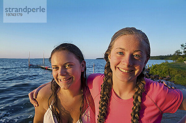 Außenporträt zweier Mädchen im Teenageralter  die am Leech Lake in Minnesota  USA  für die Kamera posieren; Walker  Minnesota  Vereinigte Staaten von Amerika
