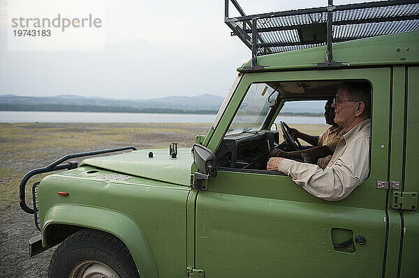 Zwei Männer fahren durch das Mweya-Gebiet in Uganda  Afrika  im Queen-Elizabeth-Nationalpark; Mweya  Uganda