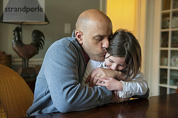 Vater zeigt seiner kleinen Tochter Zuneigung mit einer Umarmung und einem Kuss im Haus; Washington  District of Columbia  Vereinigte Staaten von Amerika