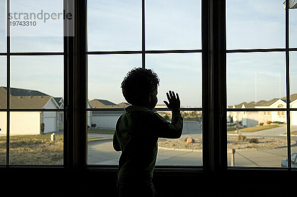 Kleinkind schaut aus dem Fenster seines Hauses auf die Nachbarschaft draußen; Lincoln  Nebraska  Vereinigte Staaten von Amerika