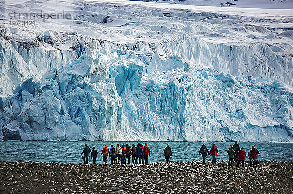 Ökotouristen in der Nähe eines blauen Eisgletschers über dem Krossfjord; Spitzbergen  Svalbard-Archipel  Norwegen