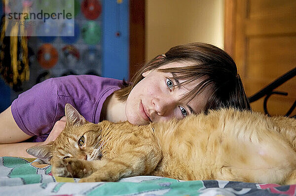 Mädchen entspannt sich und streichelt ihre Katze (Felis silvestris catus) in ihrem Schlafzimmer; Lincoln  Nebraska  Vereinigte Staaten von Amerika