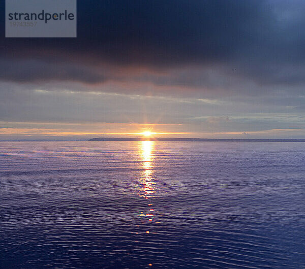 Atemberaubender Blick auf den Pazifischen Ozean in der Dämmerung mit dem Schein der Sonne über dem malvenfarbenen Wasser; Crescent Beach  Surrey  British Columbia  Kanada