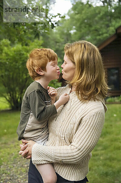 Mutter küsst ihren kleinen weißen Sohn  der draußen steht; Cross Lake  Minnesota  Vereinigte Staaten von Amerika
