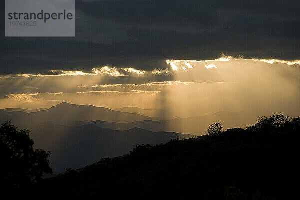 Sonnenlicht strömt bei Sonnenuntergang durch Lücken in den dunklen Wolken über den Blue Ridge Mountains; North Carolina  Vereinigte Staaten von Amerika