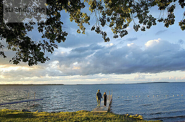 Mutter und ihre Tochter gehen in der Abenddämmerung Händchen haltend einen Steg an einem See hinunter  Leech Lake in Minnesota  USA; Walker  Minnesota  Vereinigte Staaten von Amerika