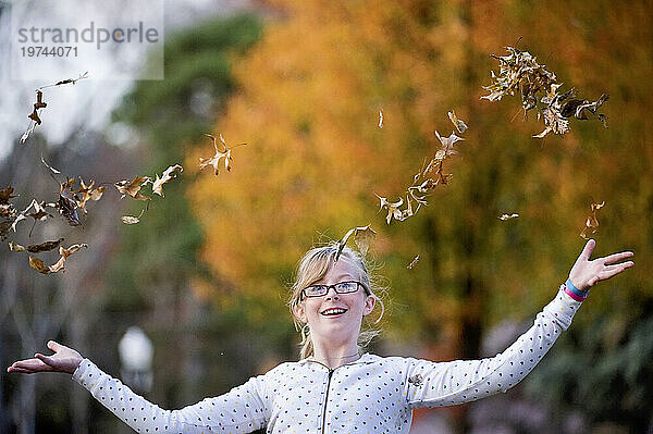 Mädchen spielt an einem schönen Herbsttag draußen und wirft Blätter in die Luft; Lincoln  Nebraska  Vereinigte Staaten von Amerika
