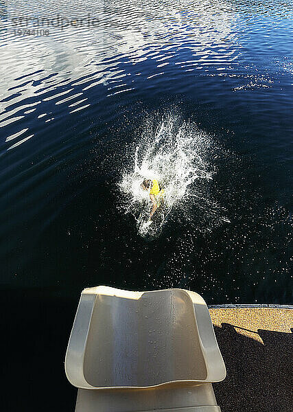 Junge planscht ins Wasser  nachdem er aus dem Ende einer Hausboot-Wasserrutsche am Shuswap Lake gerutscht ist; British Columbia  Kanada