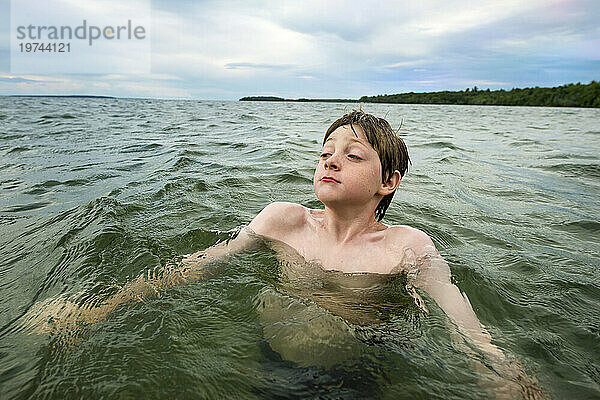 Junge schwimmt in einem kalten See; Walker  Minnesota  Vereinigte Staaten von Amerika