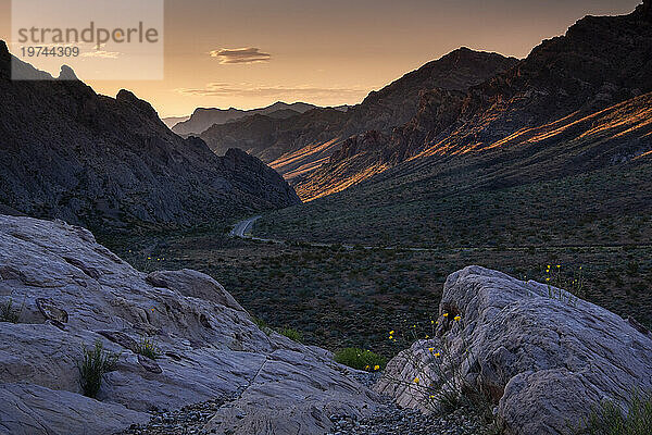 Der Sonnenaufgang beleuchtet den Pass durch die Berge am westlichen Eingang zum Valley of Fire State Park  Nevada  Vereinigte Staaten von Amerika  Nordamerika