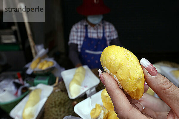 Eine Frau bereitet Durian-Früchte zum Verkauf an einem bei Touristen und Einheimischen beliebten Streetfood-Stand in Bangkok  Thailand  Südostasien  Asien vor