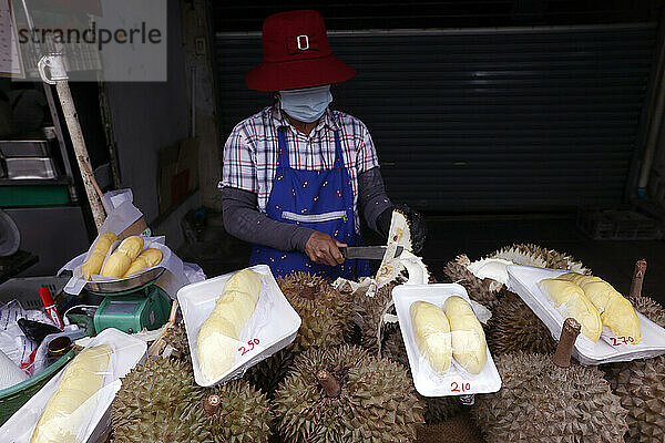 Eine Frau bereitet Durian-Früchte zum Verkauf an einem bei Touristen und Einheimischen beliebten Streetfood-Stand in Bangkok  Thailand  Südostasien  Asien vor