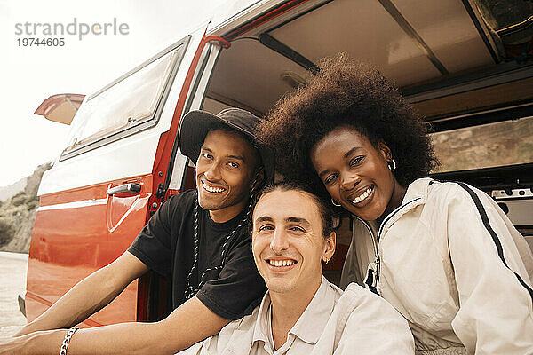 Porträt lächelnder gemischtrassiger männlicher und weiblicher Freunde  die in einem Lieferwagen sitzen