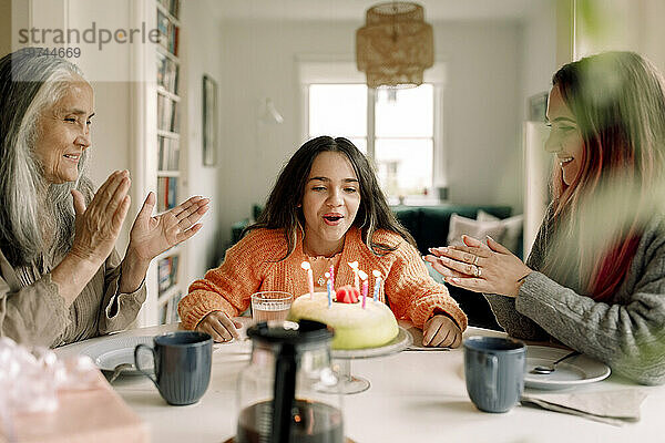 Fröhliches Mädchen  das zu Hause mit Mutter und Großmutter Geburtstag feiert