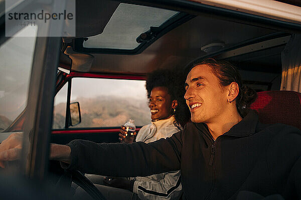 Lächelnder junger Mann fährt mit Freundin im Urlaub Lieferwagen