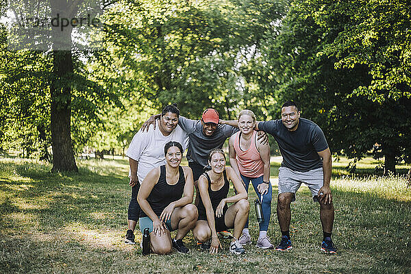 Porträt glücklicher  gemischtrassiger männlicher und weiblicher Freunde  die nach dem Training im Park posieren