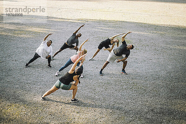 Blick aus der Vogelperspektive auf eine Trainerin beim Stretching mit der Mannschaft im Park