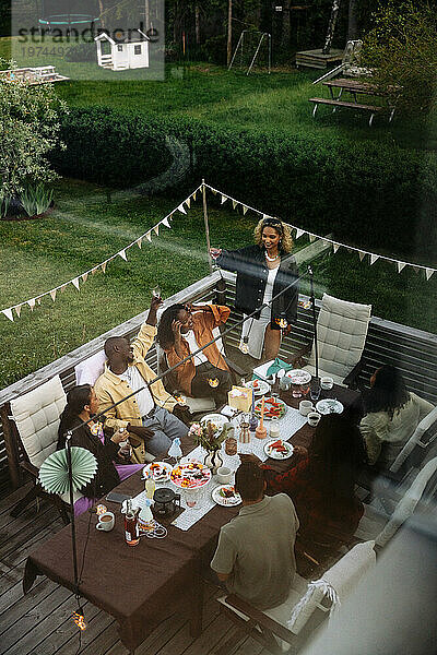 Blick aus der Vogelperspektive auf männliche und weibliche Freunde  die eine Dinnerparty im Hinterhof genießen