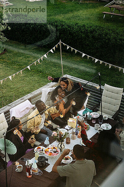 Männliche und weibliche Freunde amüsieren sich während der Dinnerparty im Hinterhof