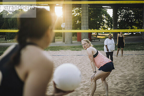 Reife Frau schaut Freund an  der Volleyball hält