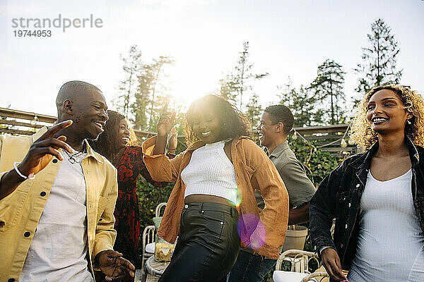 Fröhliche männliche und weibliche Freunde tanzen beim Feiern während der Party im Hinterhof