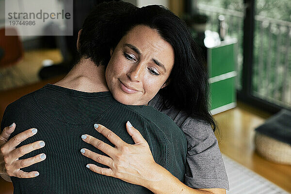 Traurige Mutter umarmt Sohn zu Hause